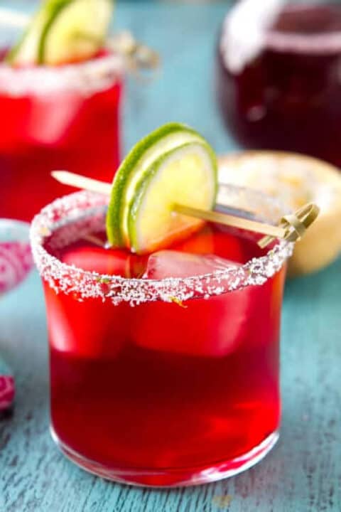 Hibiscus margarita in a glass with a lime garnish.