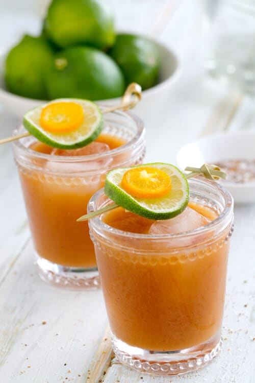 Tamarind margarita in two glasses with a lime and kumquat garnish.