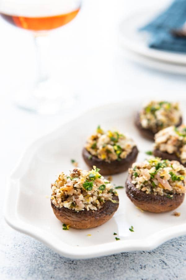 Platter of Stuffed Spanish Mushrooms with a glass of wine in the background.