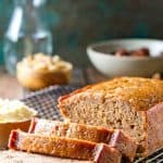 Date Nut bread recipe on a cooling rack with several cut slices next to a pot of butter.