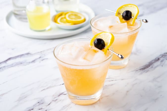 close up of the vodka sour with a plate of the recipe ingredients in the background.