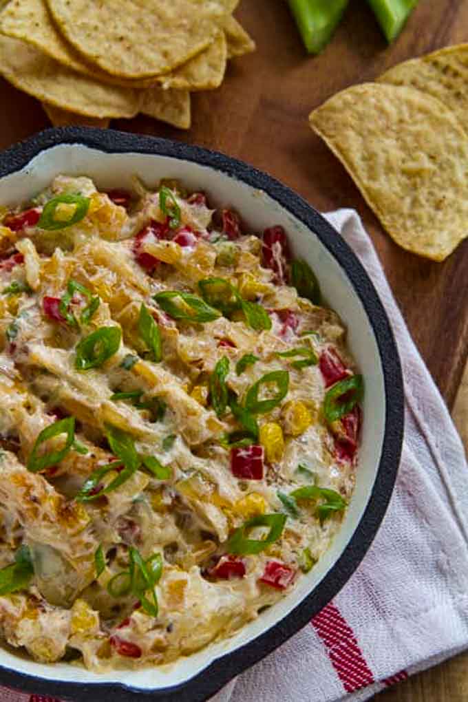 Skillet with crack corn dip with tortilla chips in the background.