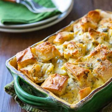 savory bread pudding recipe in a casserole dish with plates and silverware in the background.