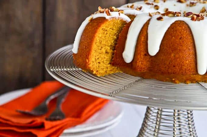 Bourbon Pumpkin Bundt cake for Thanksgiving on a cake stand with a slice pulled out.