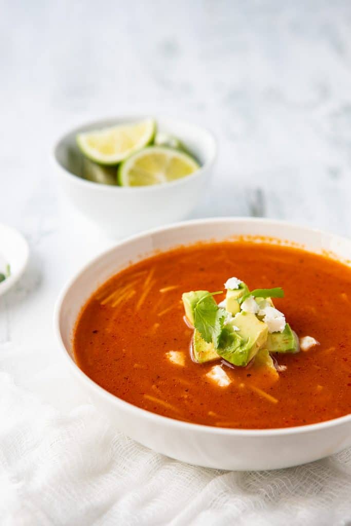 Bowl of Sopa de Fideo on a napkin with a garnish of avocado