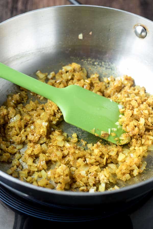 Sweet, sour and spicy, this Tomato Chutney is everything you love about ketchup - but better! Flavored with ginger , curry and a little chile, you'll want to slather this chutney on everything - chicken, fish, steaks, sandwiches and vegetables! A quick saute and simmer is all it takes for this riff on an Indian classic! saute pan with onions and spices for tomato chutney