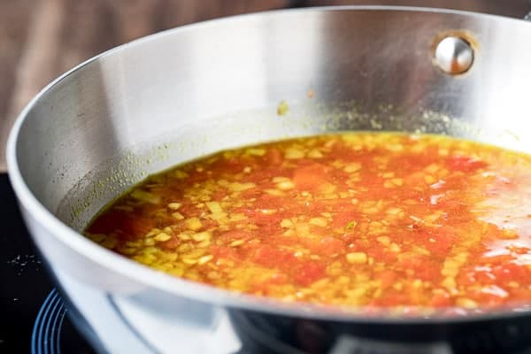 Sweet, sour and spicy, this Tomato Chutney is everything you love about ketchup - but better! Flavored with ginger , curry and a little chile, you'll want to slather this chutney on everything - chicken, fish, steaks, sandwiches and vegetables! A quick saute and simmer is all it takes for this riff on an Indian classic! Ingredients for tomato chutney in a saute pan ready to cook.