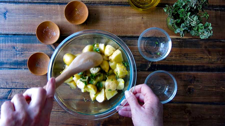 mixing the ingredients for the greek roasted potatoes 