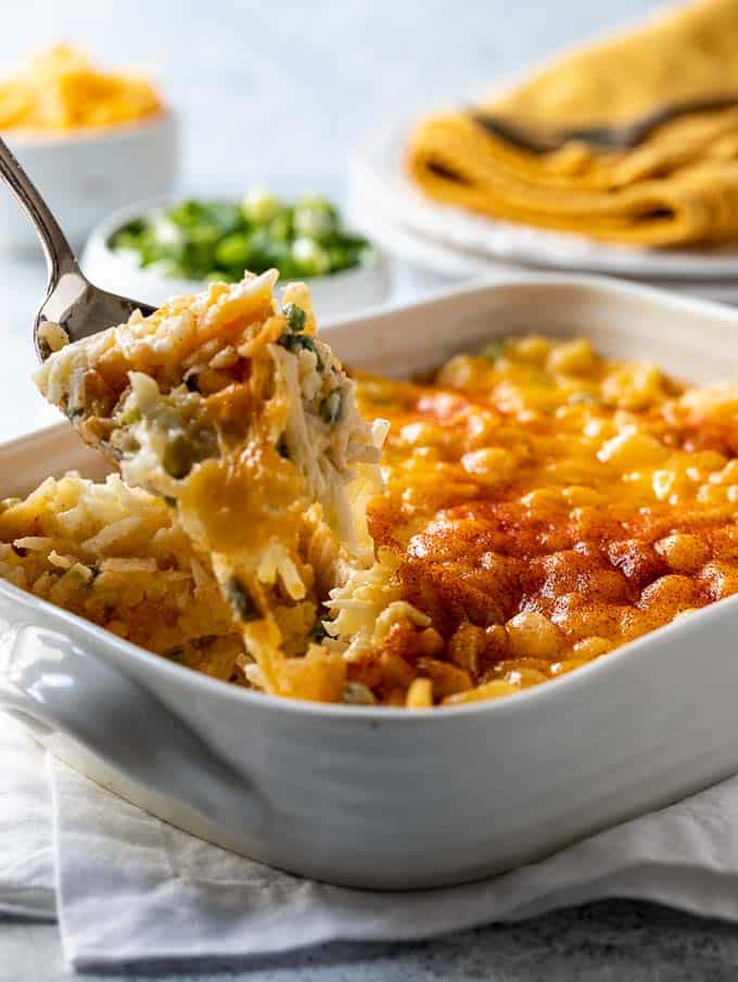 Easy cheese potatoes in a casserole dish with a portion being scooped out. 
