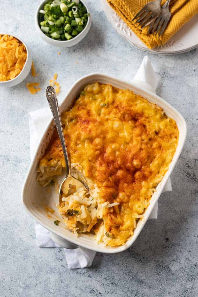 Overhead photo of this shredded potato casserole recipe with extra cheese and green onions on the side.
