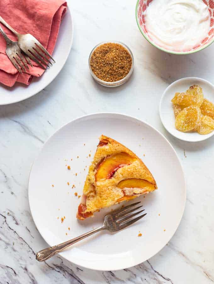 Overhead image of this easy summer cake with candied ginger, raw sugar and a bowl of softly whipped cream. 
