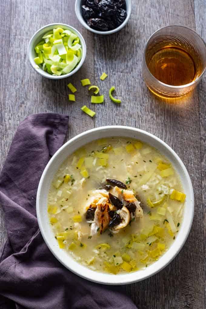 overhead photo of bowl of chicken and leek soup with prunes and whiskey.