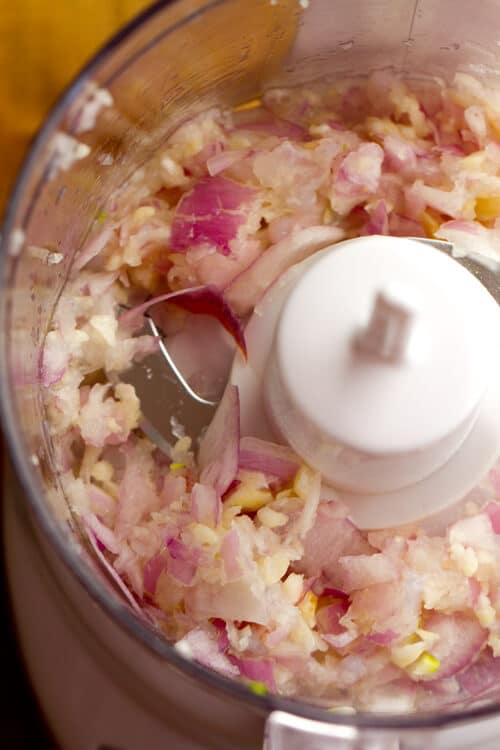 shallots and garlic in the bowl of a mini food processor for making the scampi style shrimp toast.