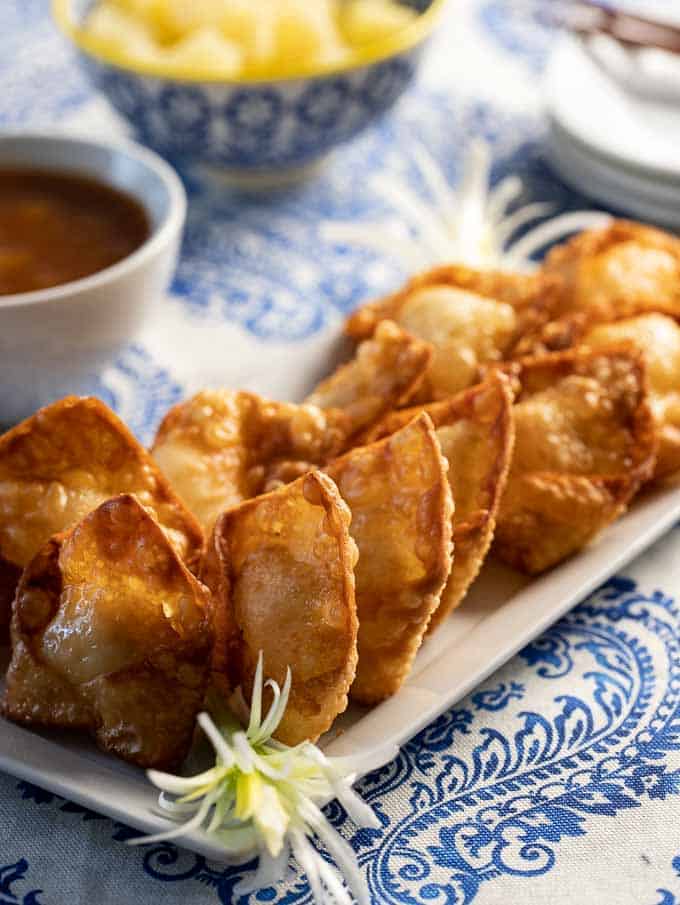 homemade 
Crab rangoon on a platter with sweet and sour dipping sauce. 