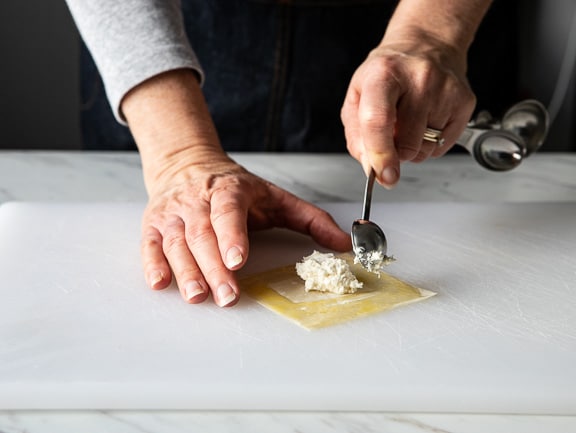 spooning the crab rangoon filling onto the wonton wrapper