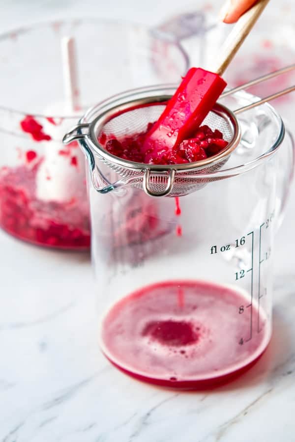 Second step in how to make grenadine - straining the arils through a mesh strainer.