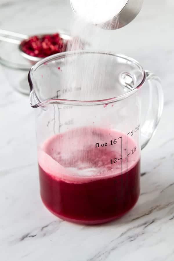 4th step in how to make grenadine - adding sugar to the pomegranate juice. 