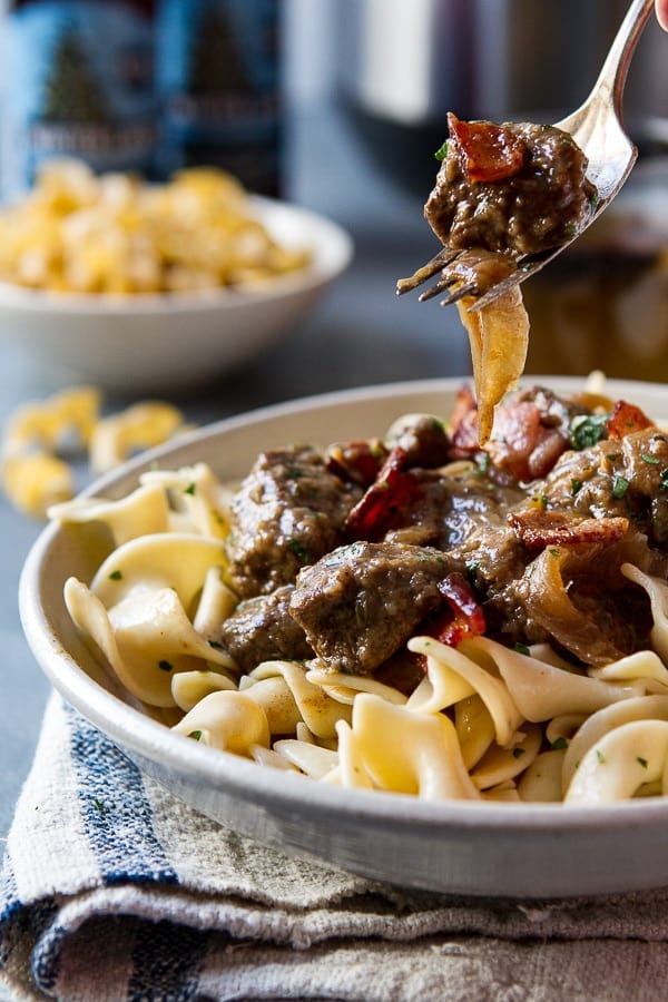 Bowl with noodles topped with Slow Cooker Beef Stew with Caramelized Onions and Beer.