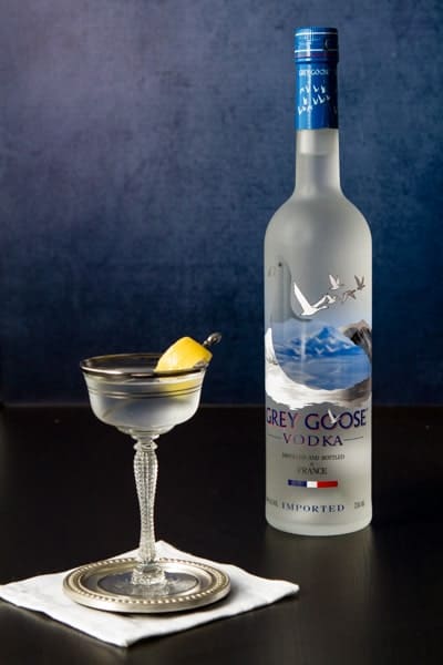 Bottle of Grey Goose Vodka and a glass with a grey goose vodka martini with a twist