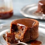 Plate with sticky toffee pudding drizzled with caramel sauce with a spoon.