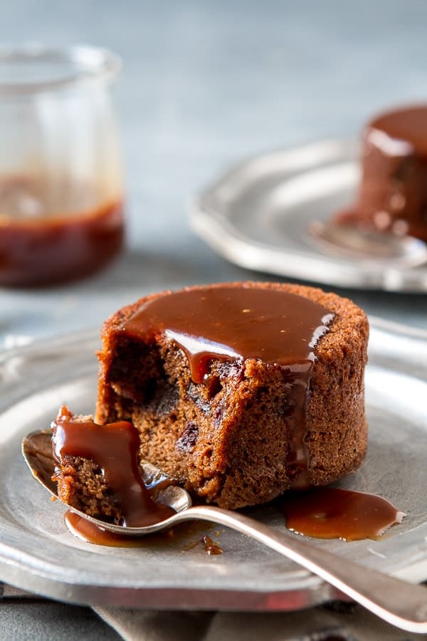  Sticky Toffee Pudding on a plate with  toffee sauce with a piece on a spoon.
