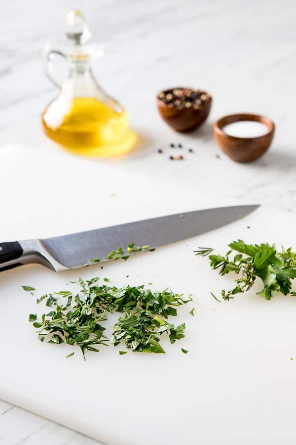 chopped herbs on a cutting board for the herb infused oil