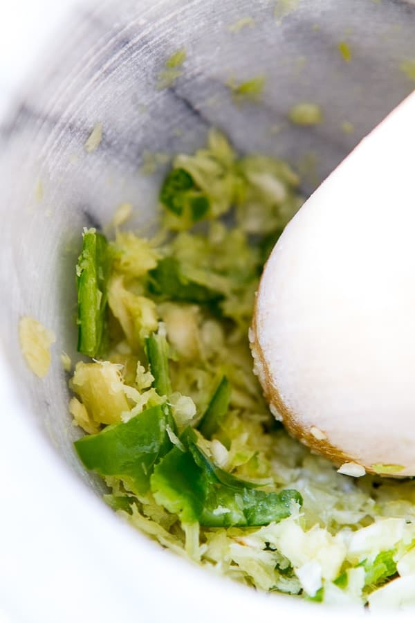 a mortar and pestle with chiles, garlic and ginger for Coconut chicken Curry