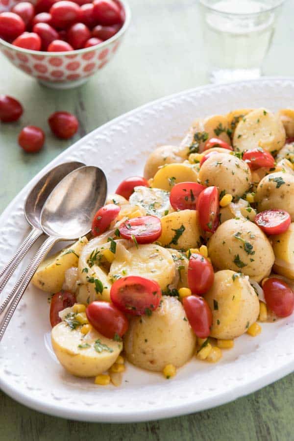 French Potato Salad on a platter with spoons. 