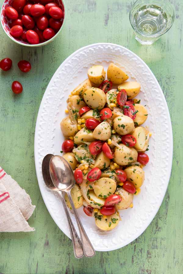 French potato salad on an oval plate with two spoons.