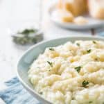 dish of instant pot risotto with herbs and parmesan in the background