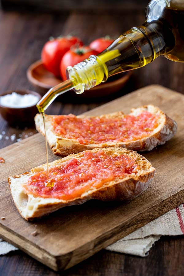 pouring olive oil on the Pan Con tomate. 