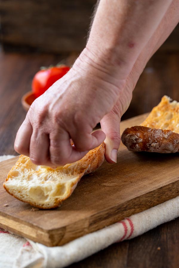 rubbing garlic on the bread for tomato bread.