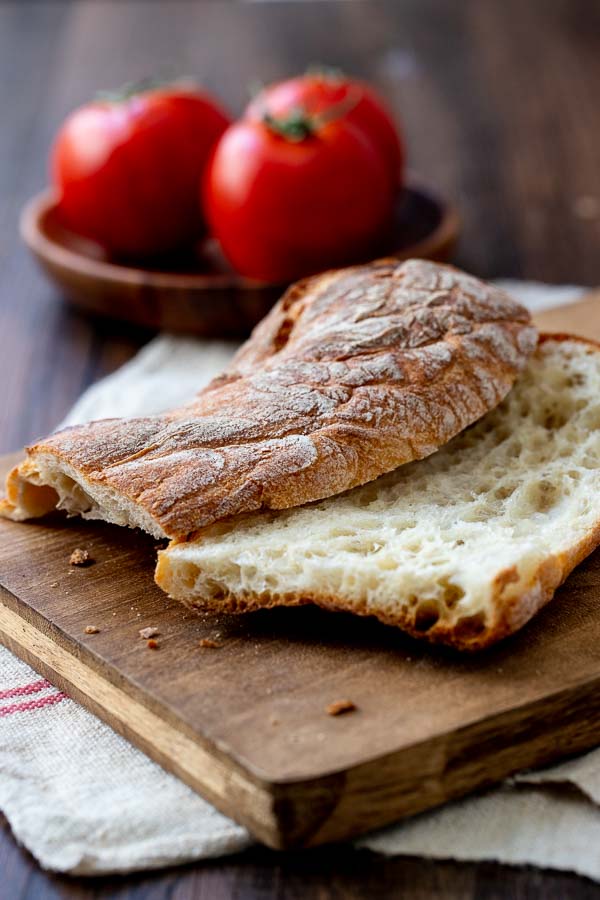 Sliced ciabatta bread on a board for tomato bread. 