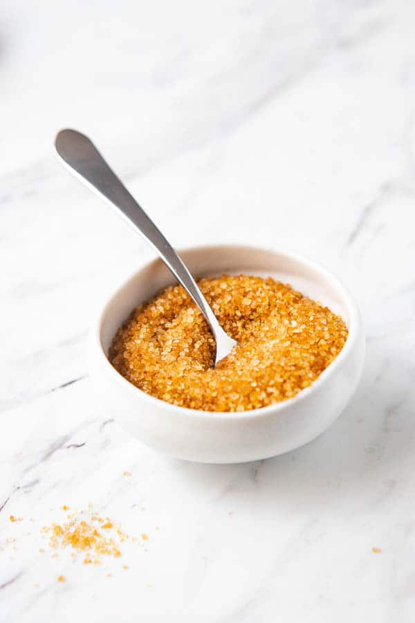 a small bowl of demerara sugar that is used for the caramelized sugar topping for this strawberries and cream dessert. 
