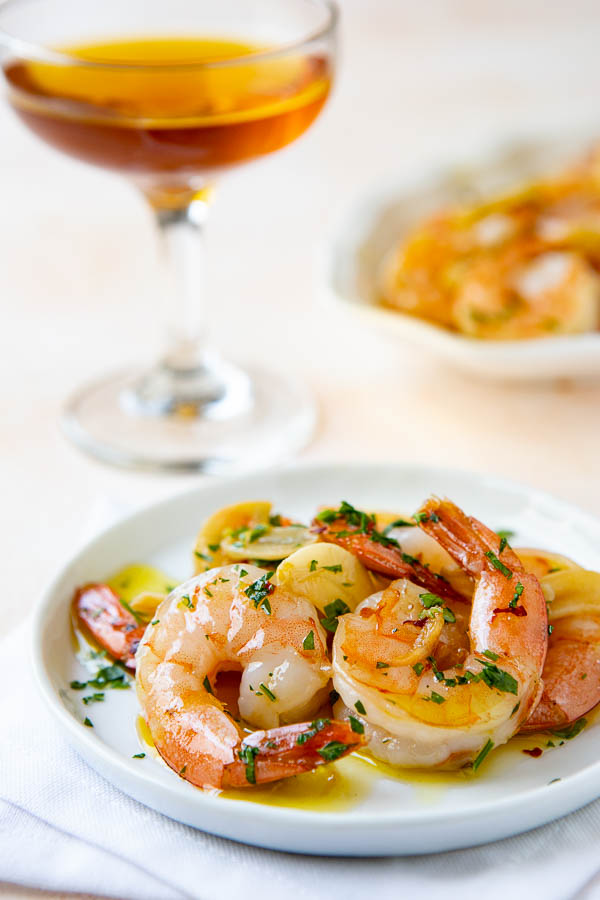 Shrimp in Garlic Sauce on a plate with a platter of garlic shrimp in the background. 