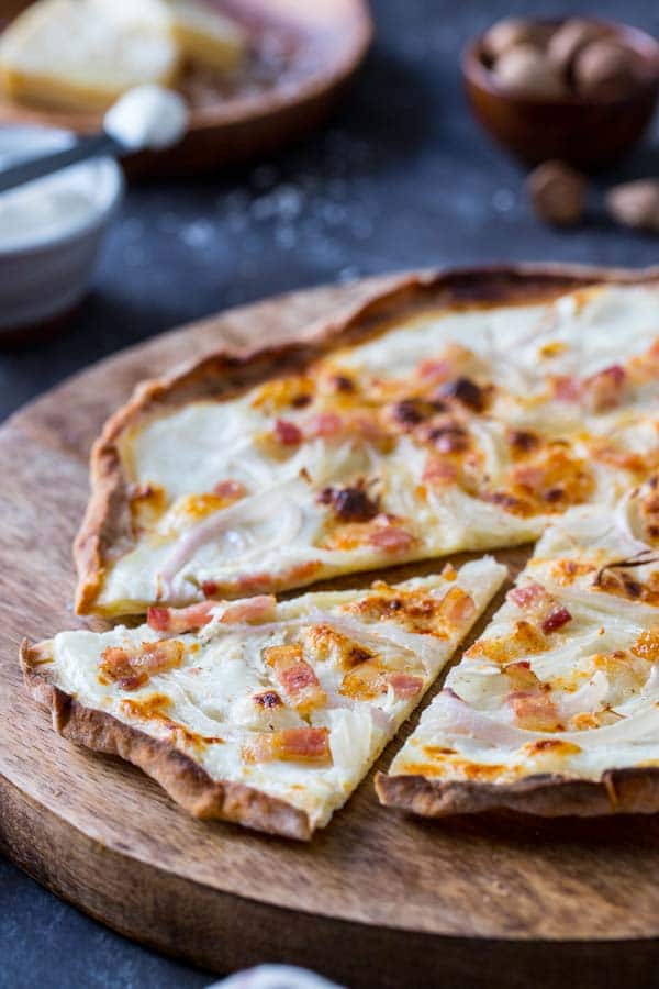 Tarte Flambee, or french pizza on a board with creme fraiche and cheese. 