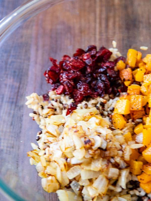 Ingredients for this baked butternut squash and wild rice pilaf recipe in a glass bowl. 