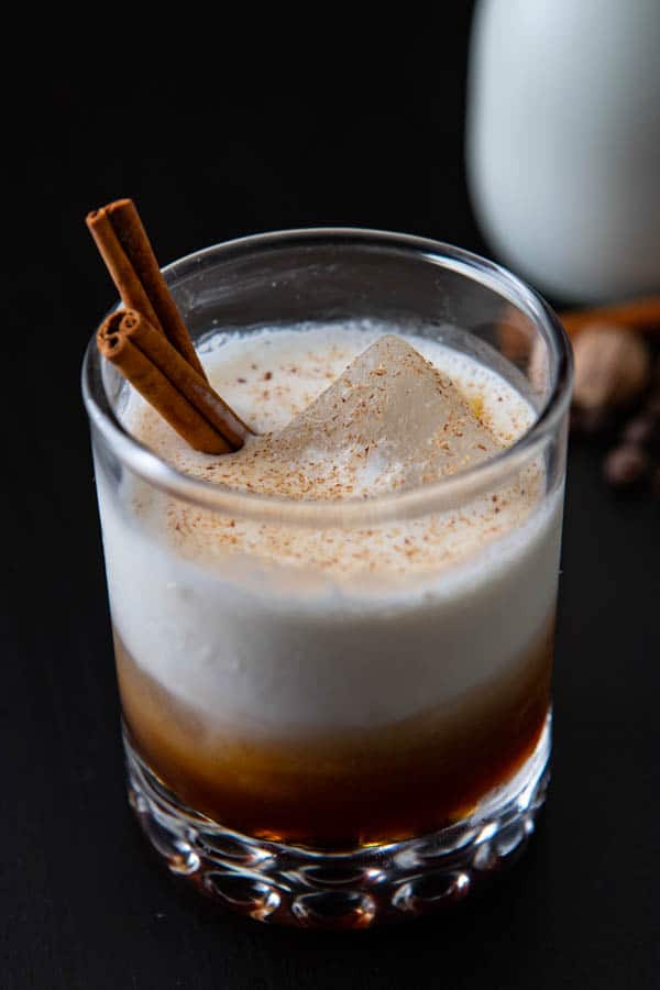 Glass with Kahlua and cream and cinnamon stirrers.