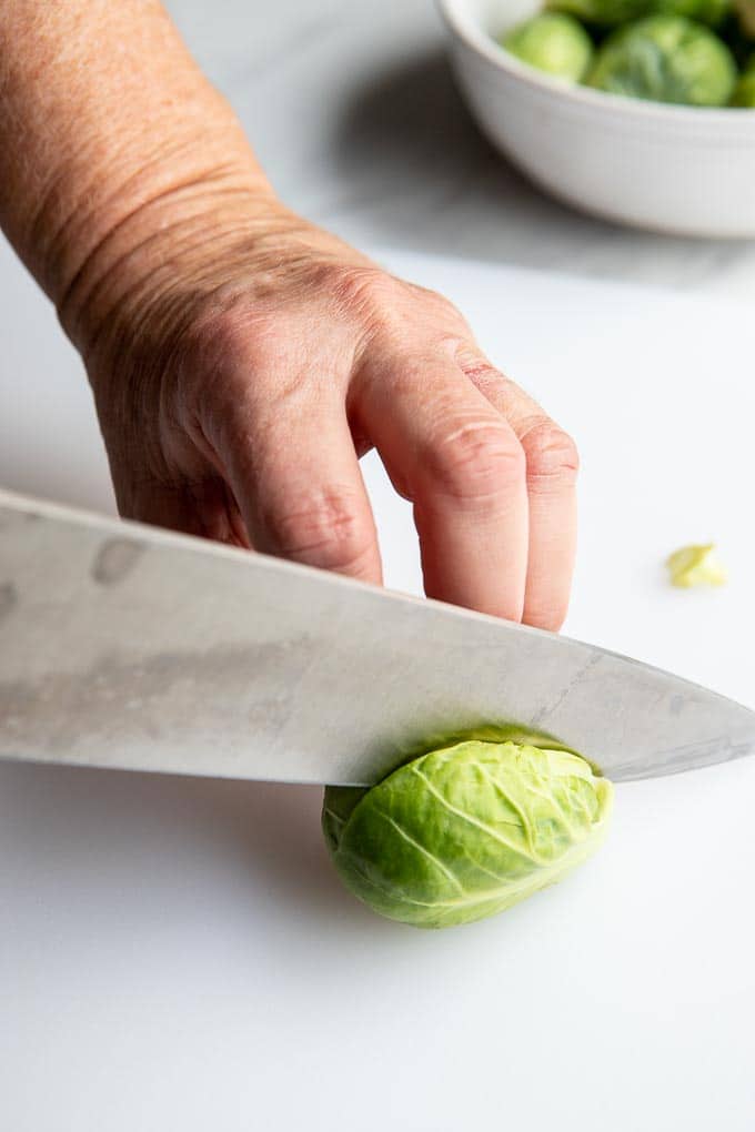 Cutting a brussels sprouts in half on a cutting board