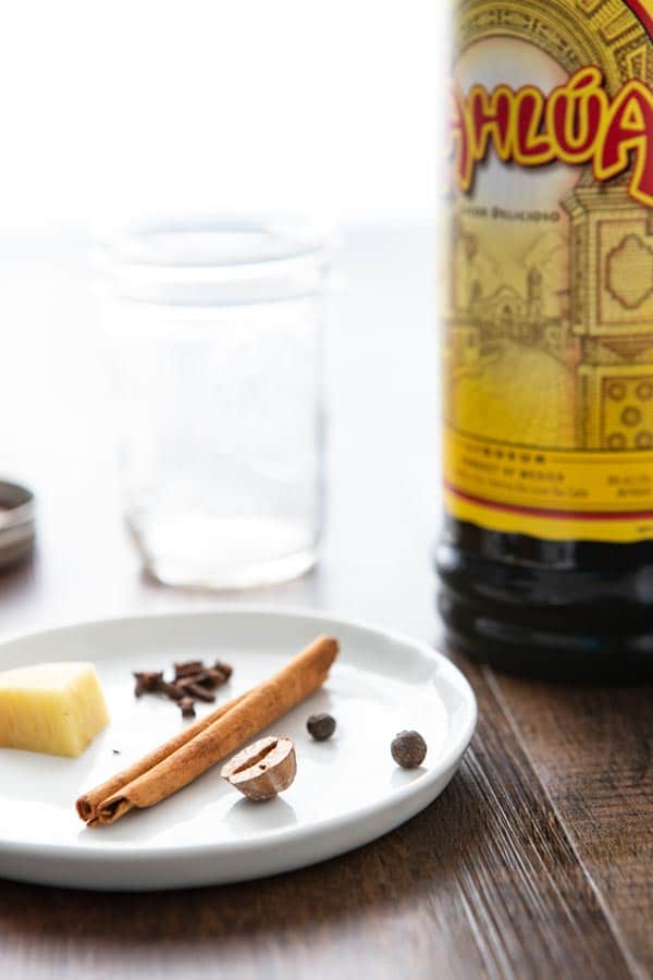 Ingredients for spice infused Kahlua  and cream recipe 
on a plate with a bottle of Kahlua.