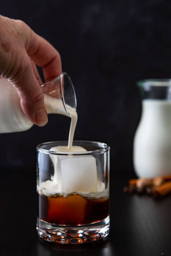 Pouring the cream over ice for the white russian drink.