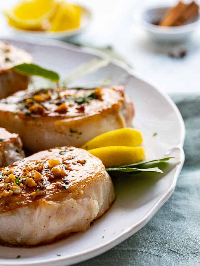 Close up of pan seared pork chops with honey garlic sauce on a platter. 
