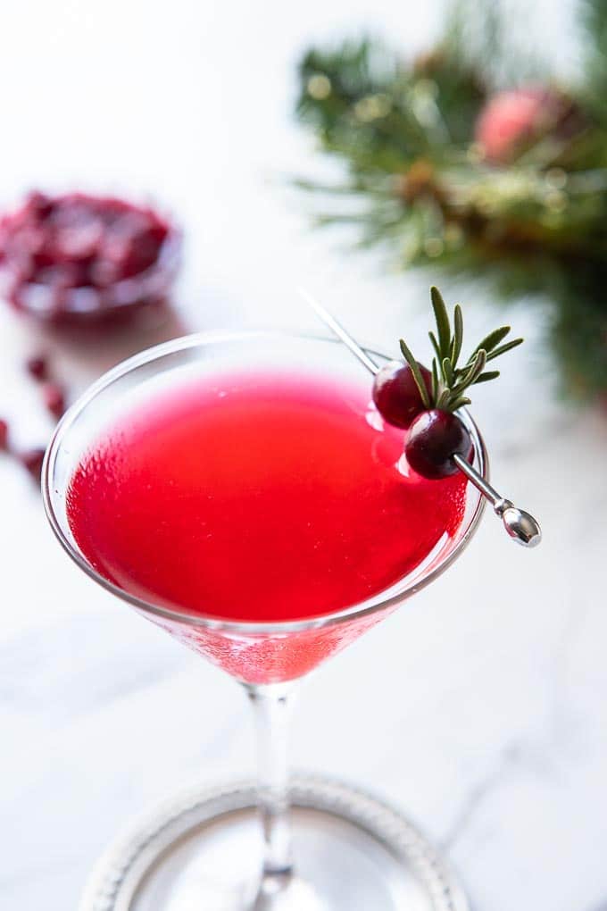 cocktail glass with cape cod cocktail and a cranberry and rosemary garnish. 