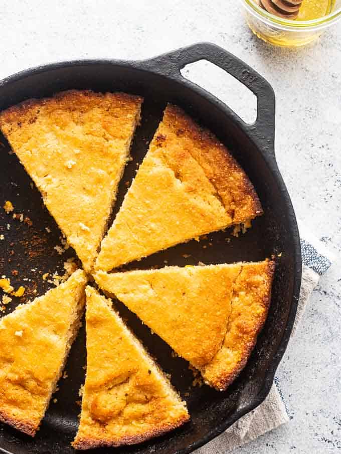 Overhead photo of brown butter cornbread in the skillet with a side of butter.