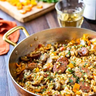 Large pan of barley risotto with italian sausage and peppers.
