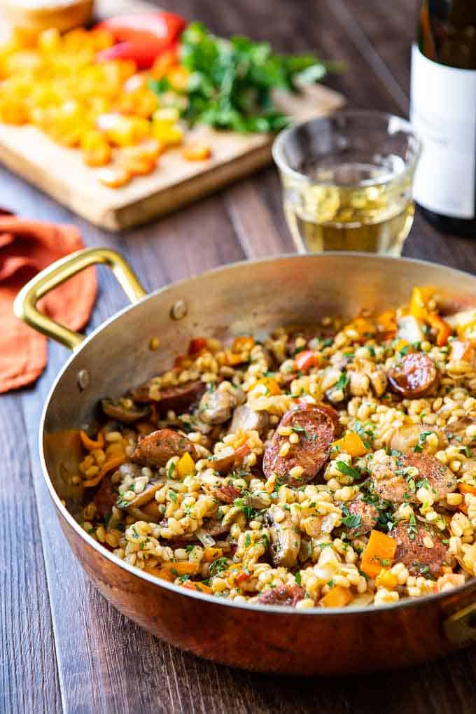 Large pan of barley risotto with italian sausage and peppers.