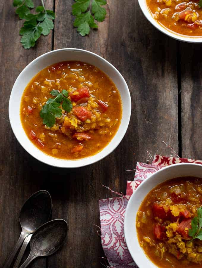 Bowls of spiced red lentil soup with coriander