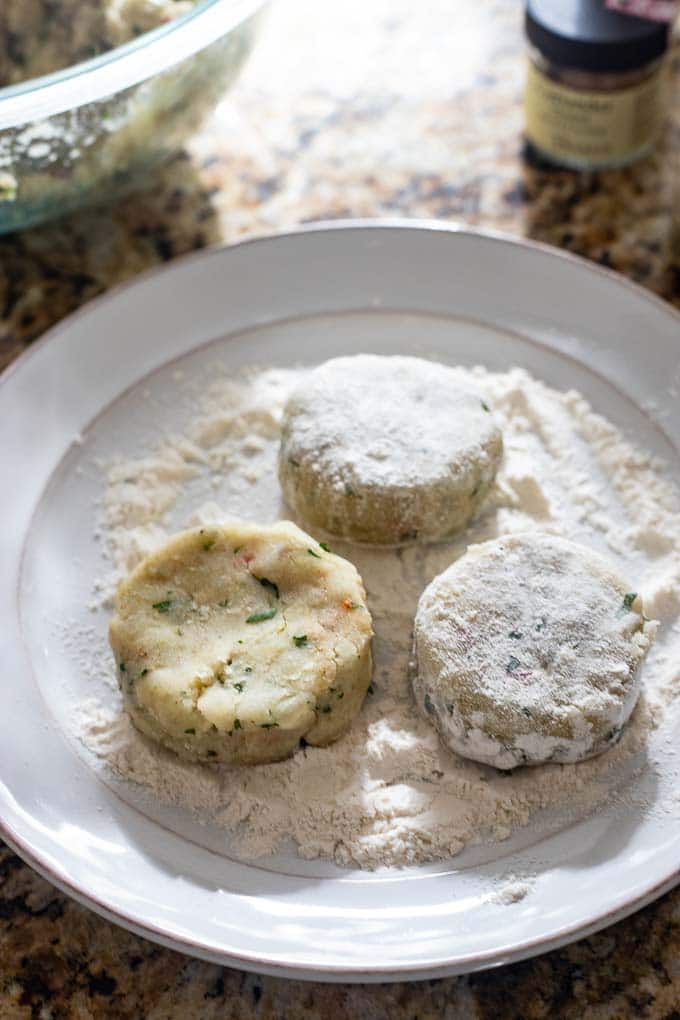 Indian potato patties being dredged in flour before cooking.