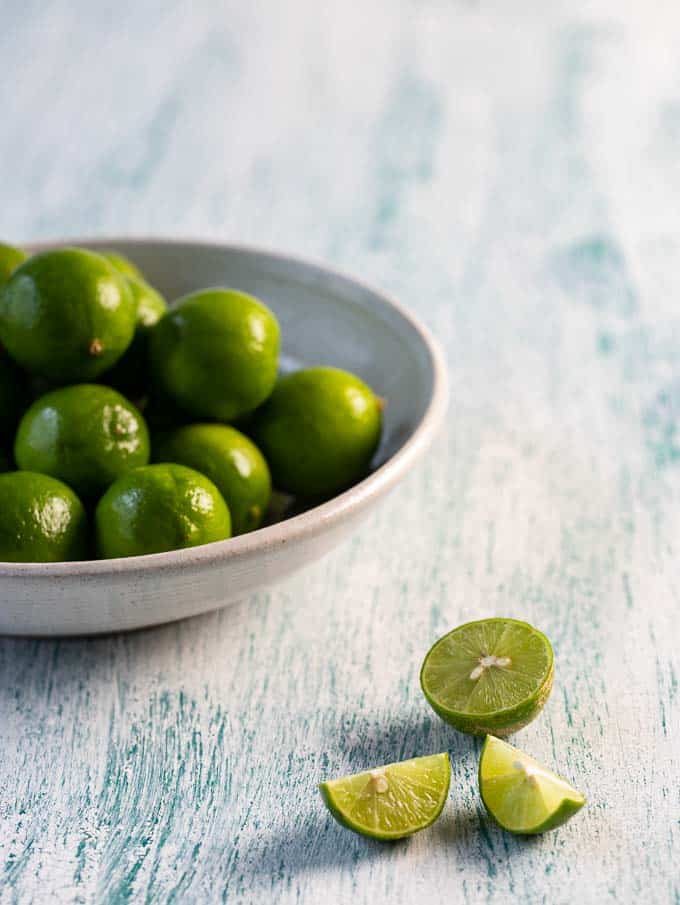 Bowl with key limes with a sliced key lime beside it to make key lime juice.