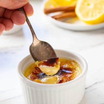 A ramekin with a spoon of spanish custard on it showing the sugar crust.